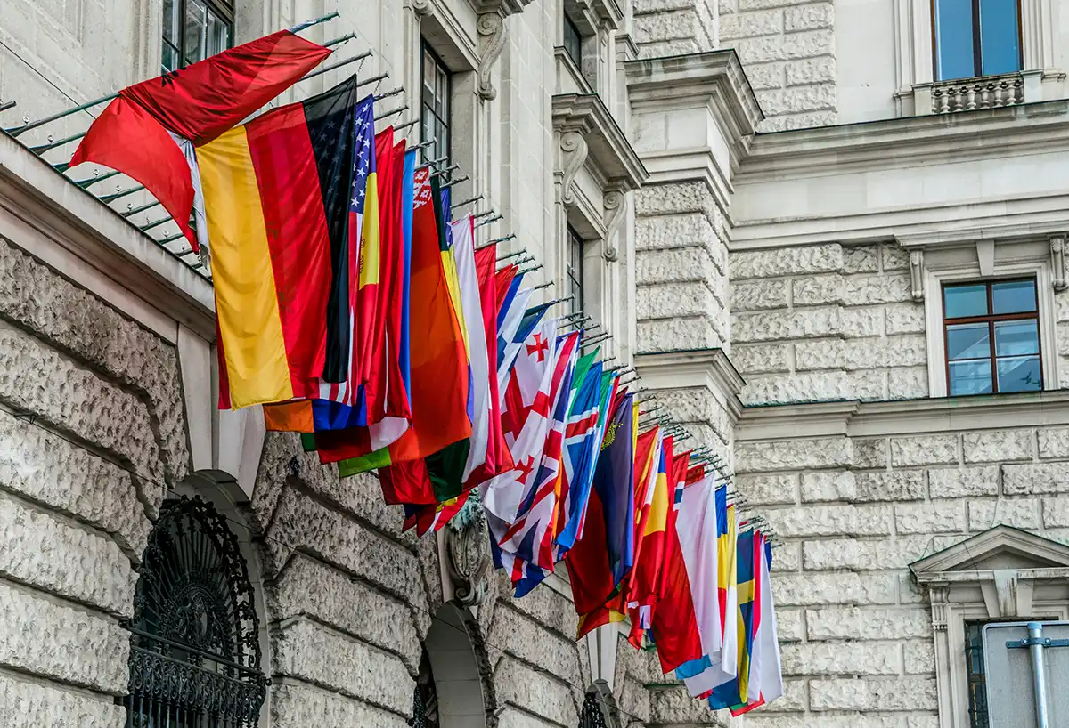 Row of national flags on the façade of a diplomatic building, symbolizing the international missions a foreign service maintains around the world.